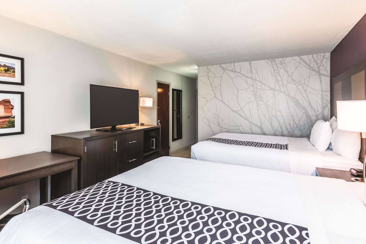 A hotel room with two beds, a TV, a desk, and a wardrobe.