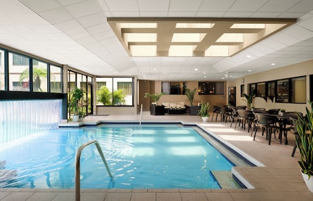 A swimming pool with a water feature, surrounded by outdoor seating and potted plants.