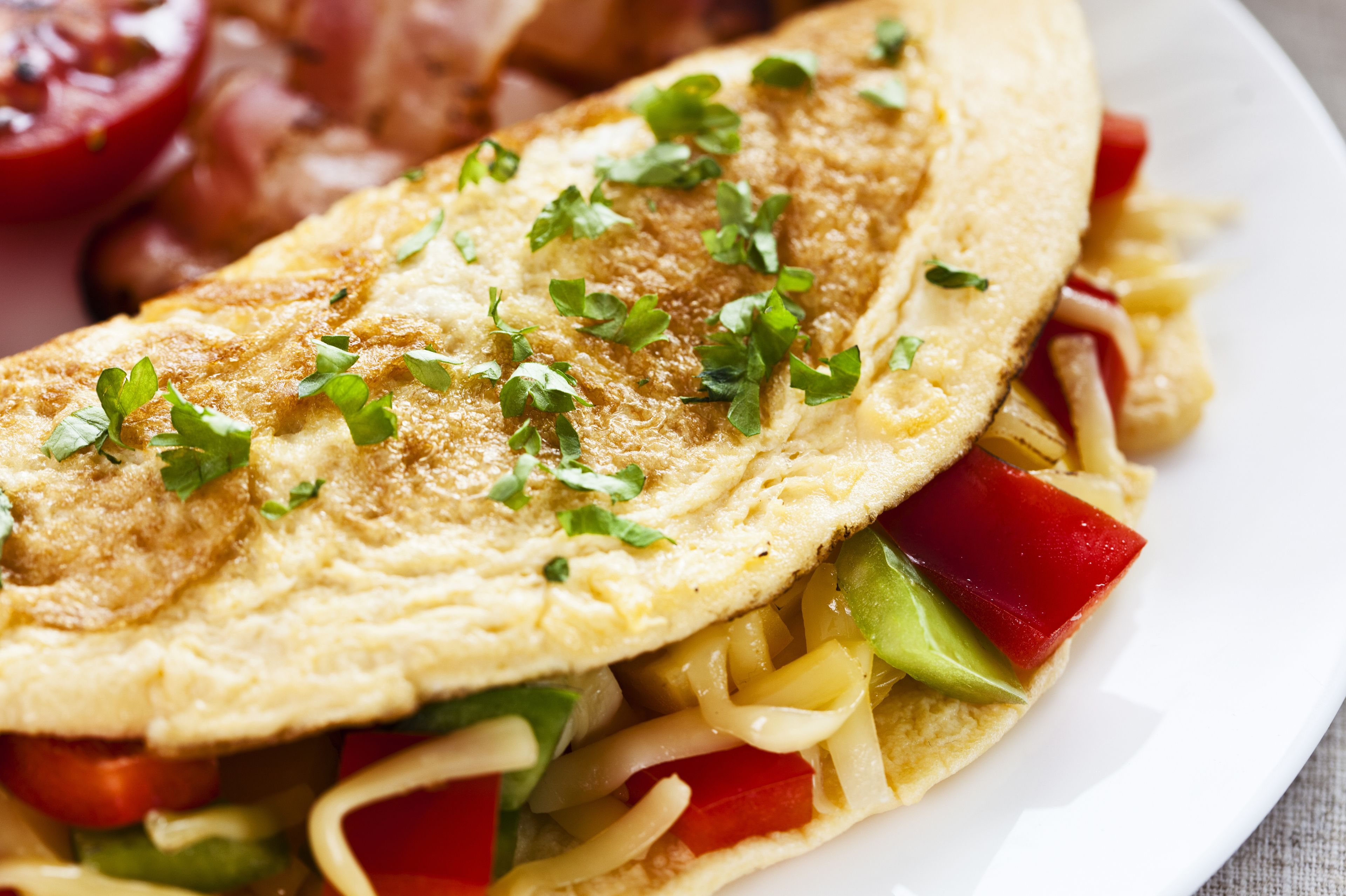 Close-up de um prato de café da manhã com omelete, legumes e queijo.