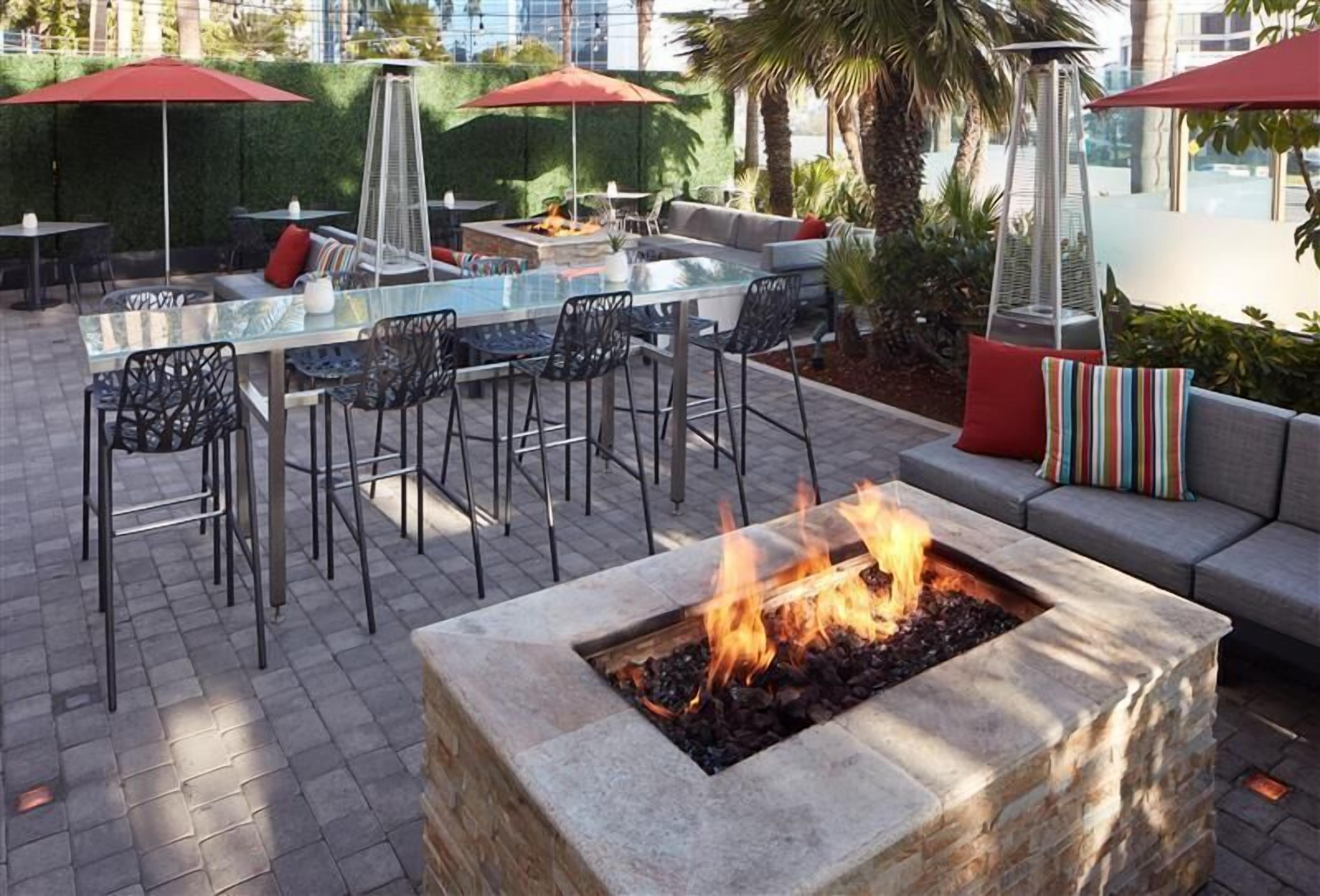 An outdoor patio with a fire pit, seating area, and umbrellas.