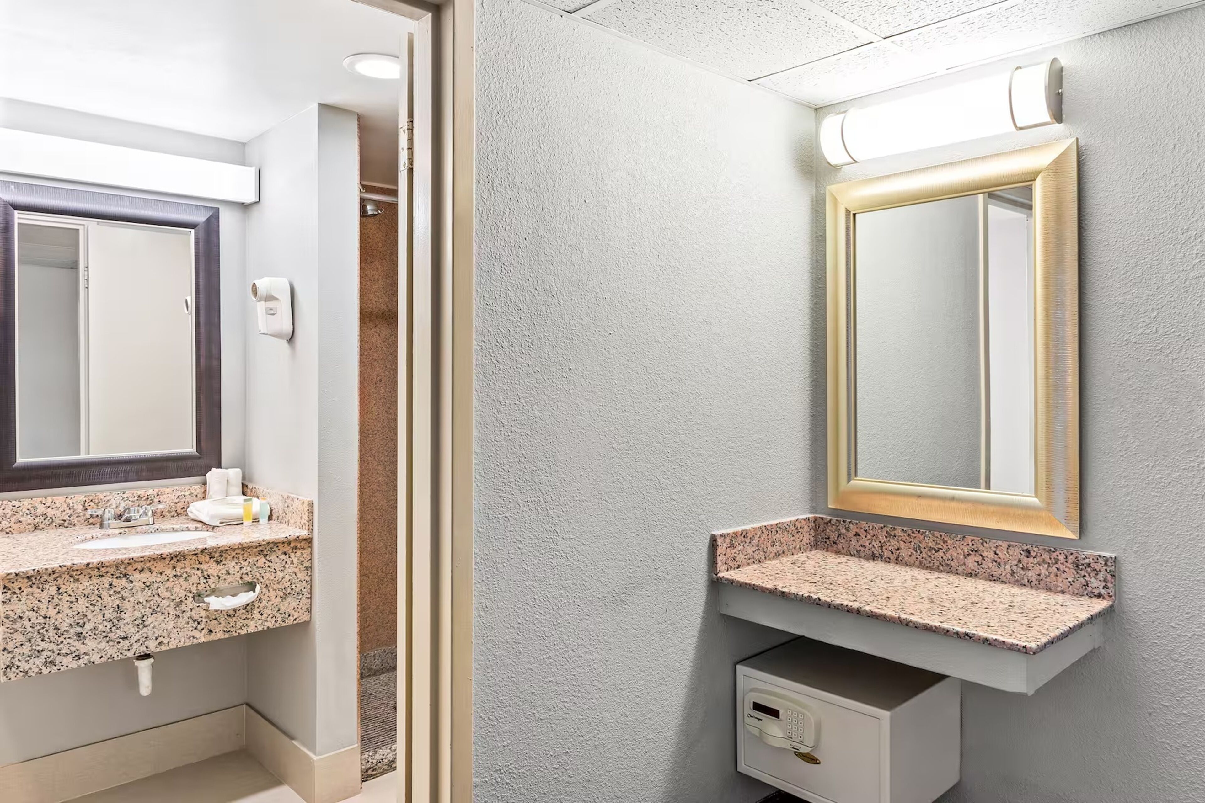 Un baño con lavamanos de encimera de granito, un espejo grande y un dispensador de toallas.