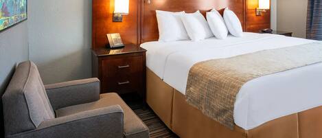 A hotel room with a large bed, two bedside tables with lamps, a chair, and a painting on the wall.