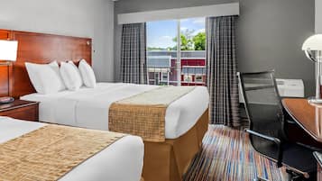 A hotel room with two beds, a desk, and a chair.