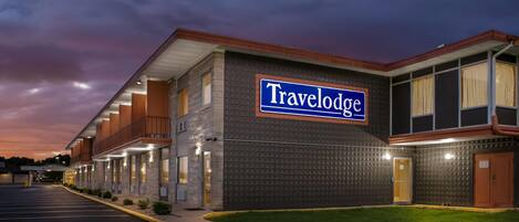 A Travelodge hotel with a brick facade, multiple windows, and a well-lit exterior.