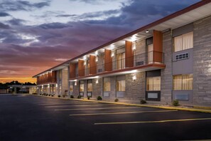 A hotel with a row of rooms, each with a balcony and large windows. - Travelodge by Wyndham Bloomington (Bloomington)