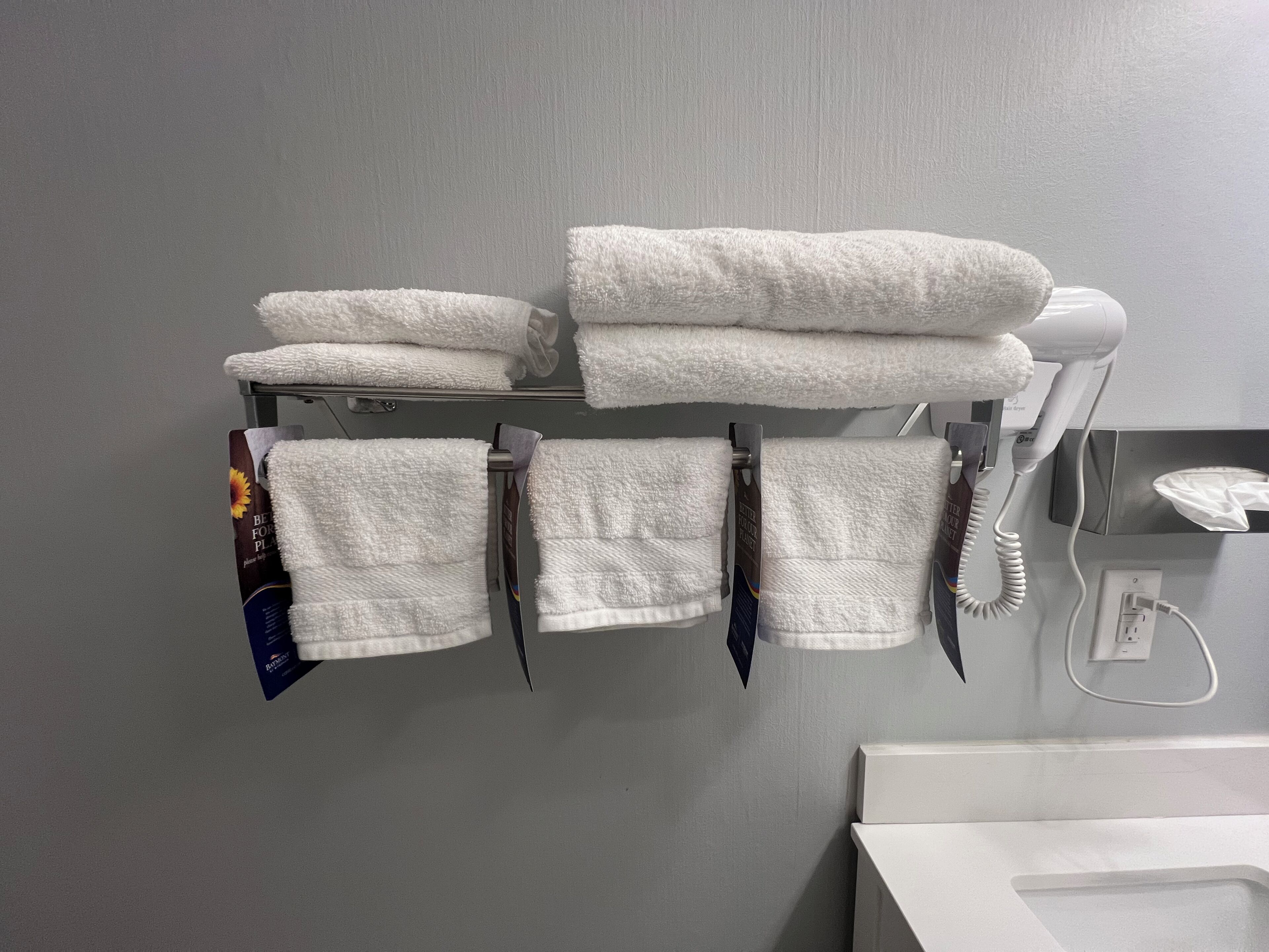 Een badkamer met een handdoekrek vol met gevouwen handdoeken en een haardroger.