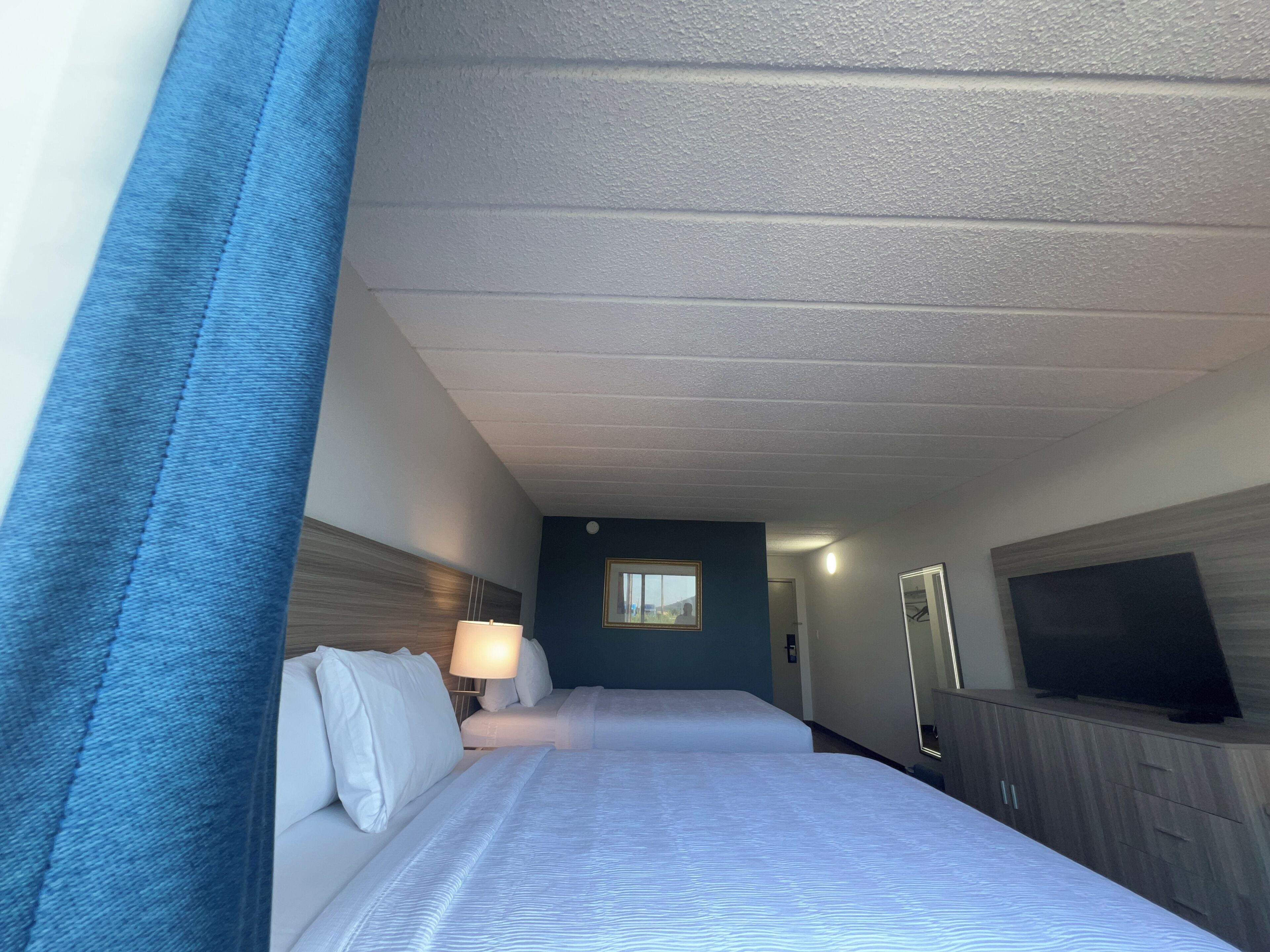 A hotel room with a bed, a TV, a desk, and a window.