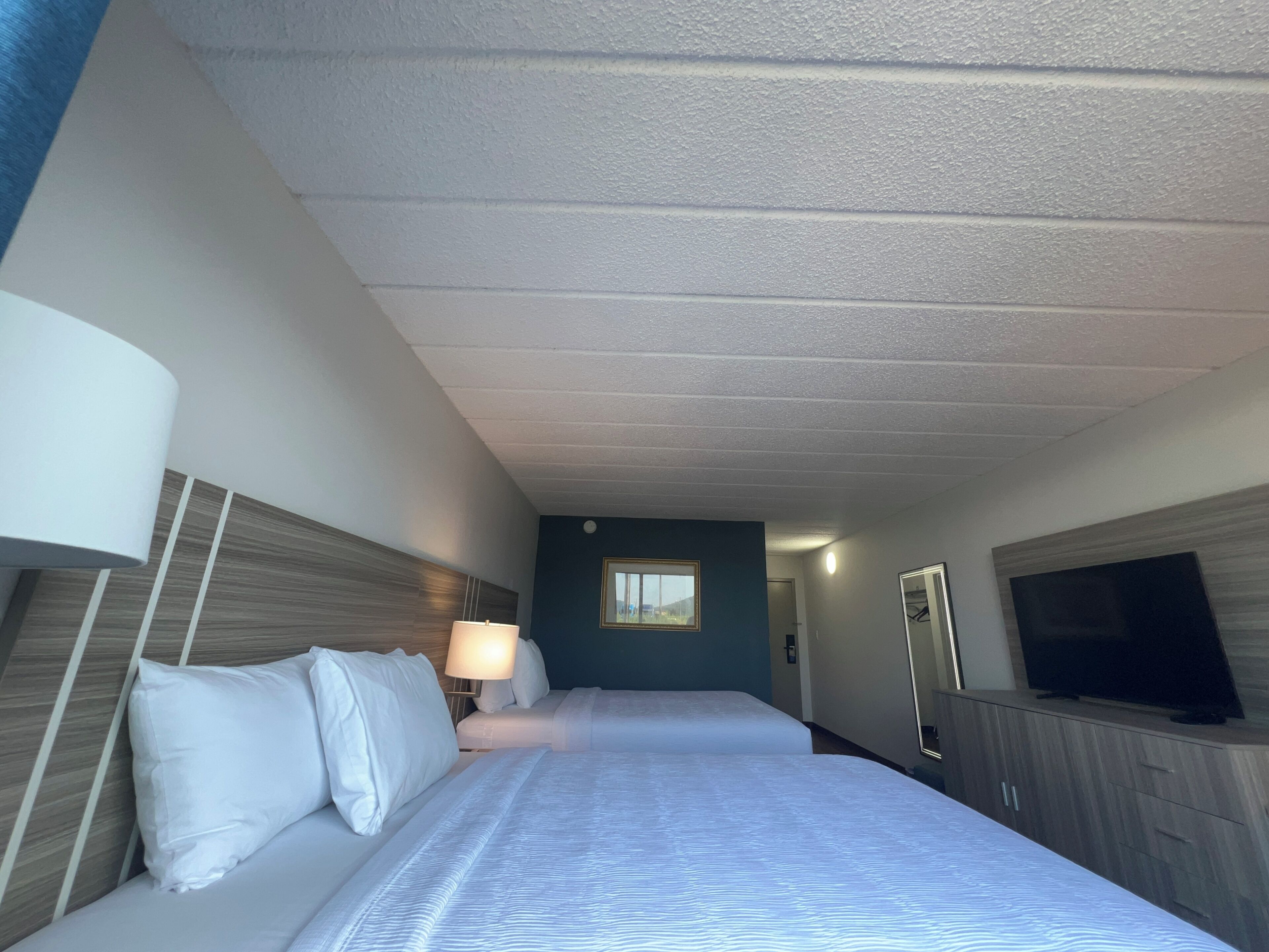 Une chambre d’hôtel avec un lit, une télévision, une lampe et une armoire.