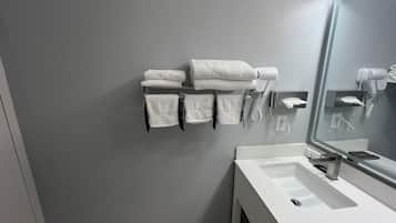 A bathroom with a white sink, a mirror, and a towel rack with folded towels.