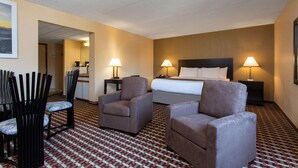 A hotel room with a bed, two armchairs, a desk, and a chair. - Days Inn by Wyndham Hillsborough (Hillsborough)