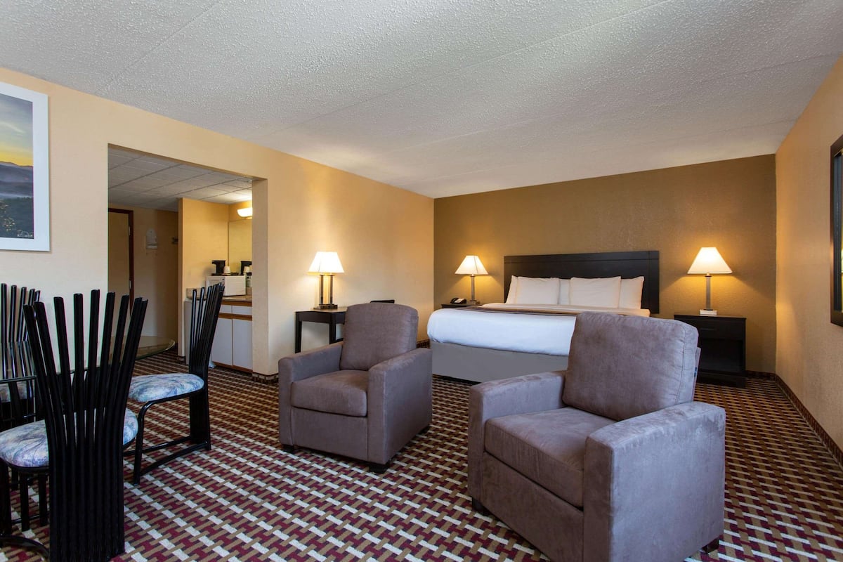 Une chambre d’hôtel comprenant un lit, deux fauteuils, un bureau et une chaise.