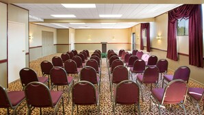 A conference room with rows of chairs, a podium, and a carpeted floor. - Days Inn by Wyndham Hillsborough (Hillsborough)