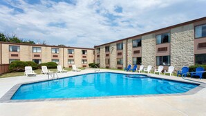 A swimming pool with lounge chairs and a building with a stone facade. - Days Inn by Wyndham Hillsborough (Hillsborough)