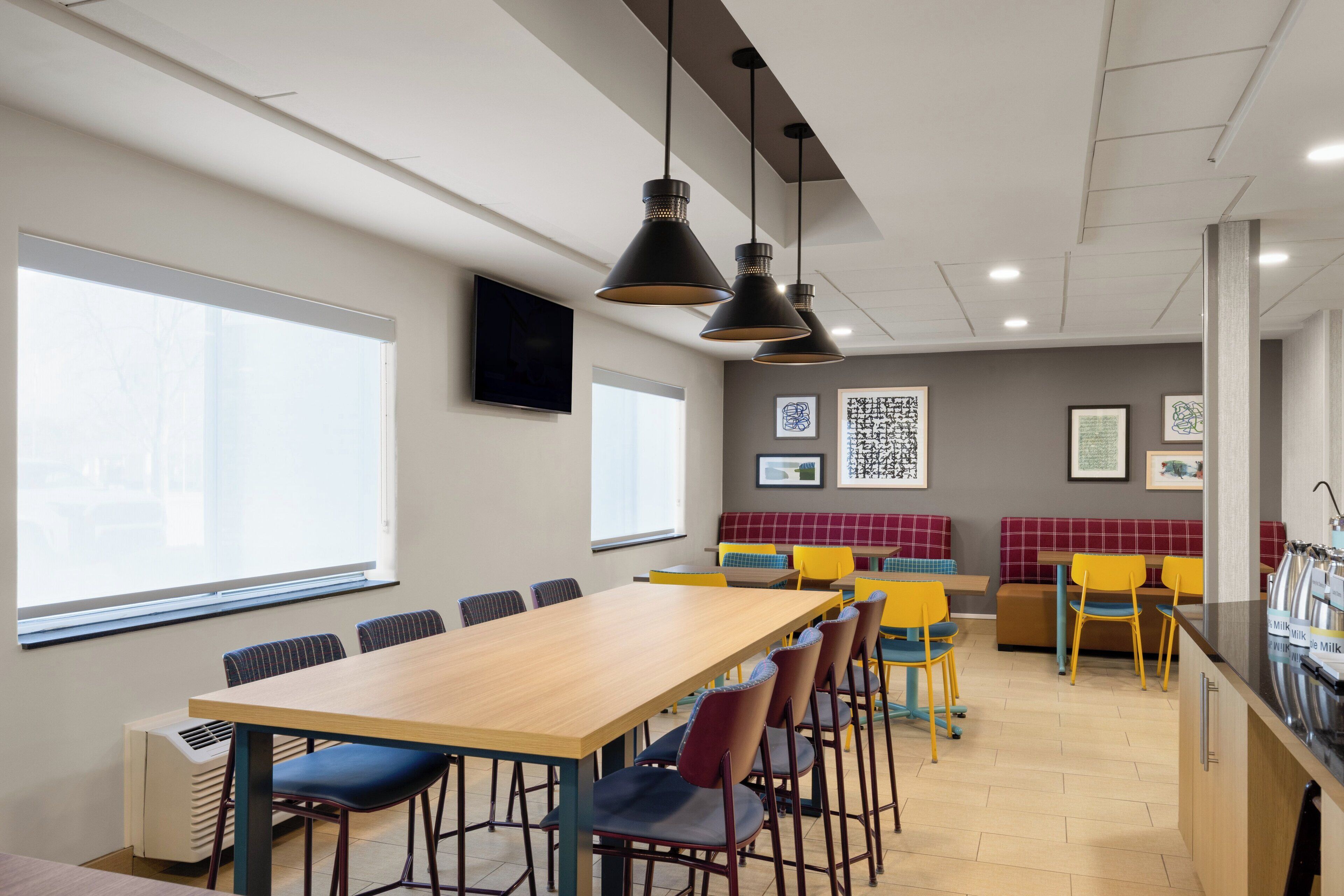 A modern meeting room with a long table, chairs, and pendant lighting.