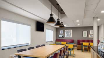 A modern meeting room with a long table, chairs, and pendant lighting.
