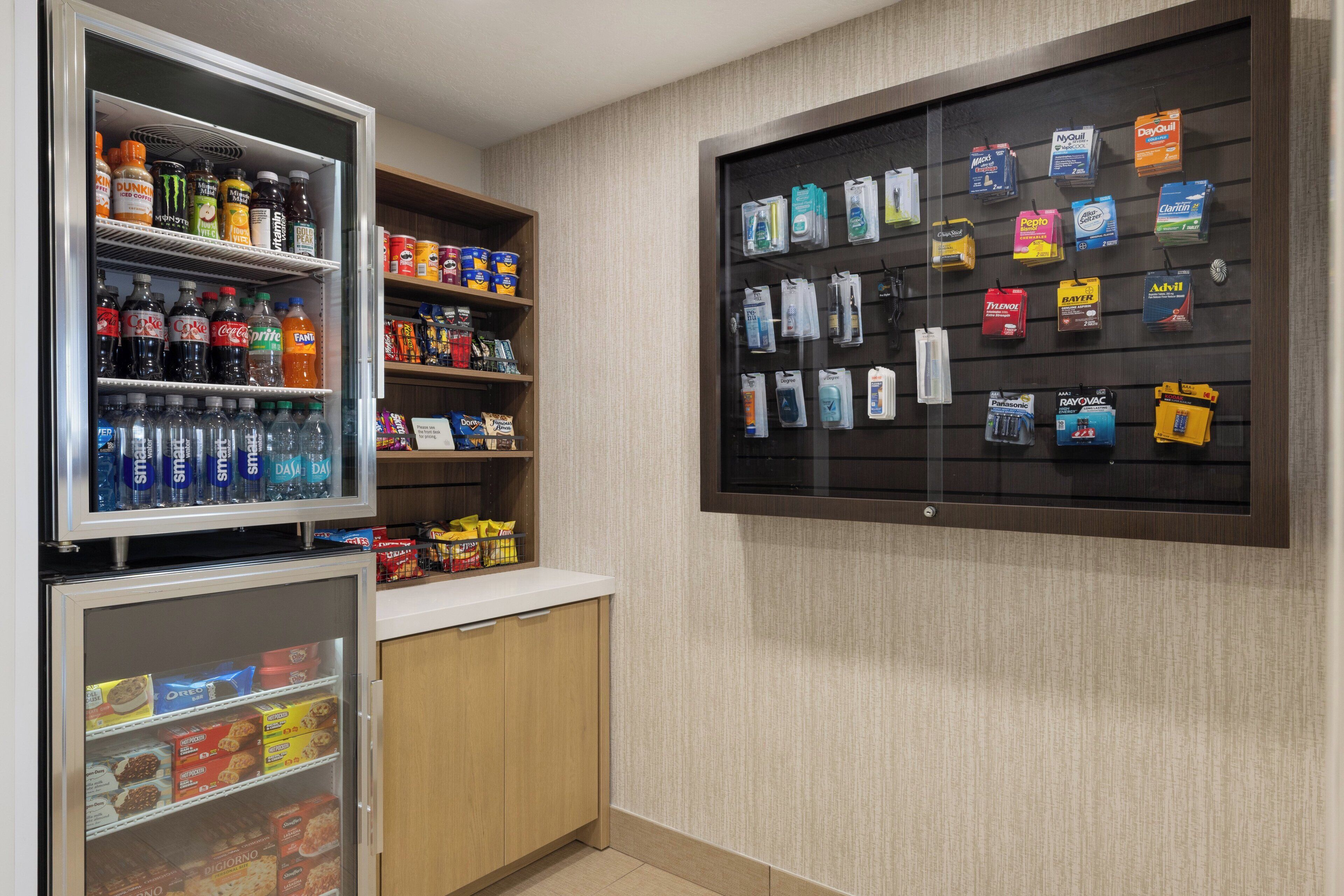 Un expositor refrigerado con diversas bebidas y aperitivos, y una pantalla de tocador montada en la pared.