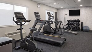 Een sportschool met loopbanden, een crosstrainer en gewichten.
