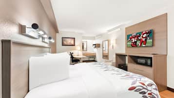 Una habitación de hotel con cama, escritorio, televisión y minibar.