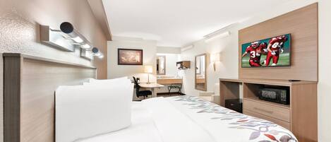 A hotel room with a bed, a desk, a television, and a minibar.