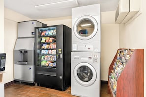 A vending machine with snacks, a coffee machine, and a stacked washer-dryer unit.