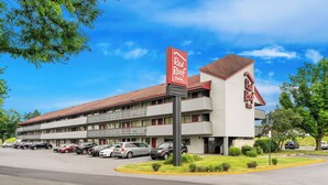 Een Red Roof Inn hotel met een gebouw van twee verdiepingen, meerdere parkeerplaatsen en een heldere lucht.