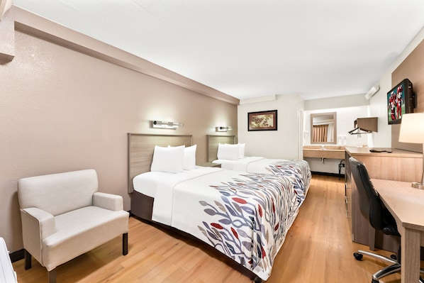 Una habitación de hotel con una cama grande, un escritorio, una silla y una pequeña cocina.