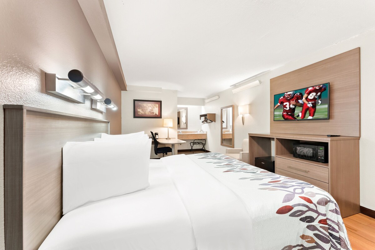 Une chambre d’hôtel équipée d’un lit, d’un bureau, d’une chaise, d’une télévision et d’un four à micro-ondes.