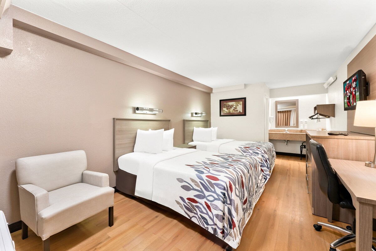 Une chambre d’hôtel avec un grand lit, un bureau, une chaise et une petite kitchenette.
