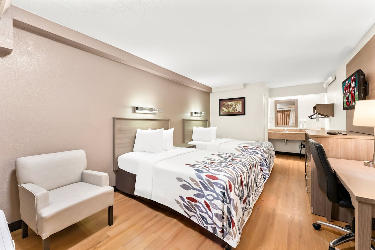 Een hotelkamer met een groot bed, een bureau, een stoel en een kleine kitchenette.