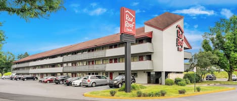 A Red Roof Inn with a parking lot and multiple cars parked in front.