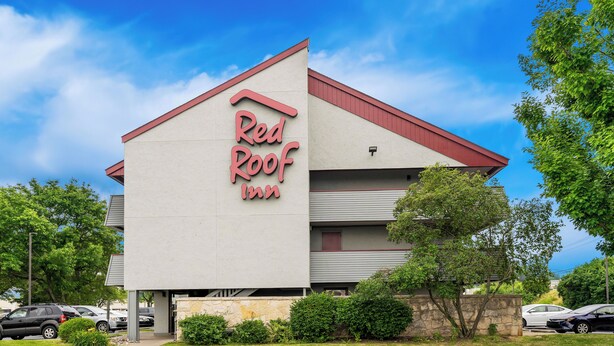 Een Red Roof Inn met een opvallend bord, een parkeerplaats en omliggend groen.