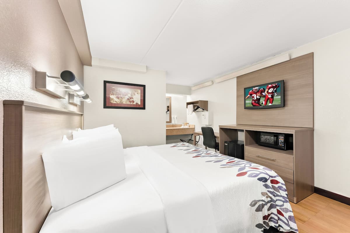 Habitación de hotel con cama, escritorio, televisor y microondas.