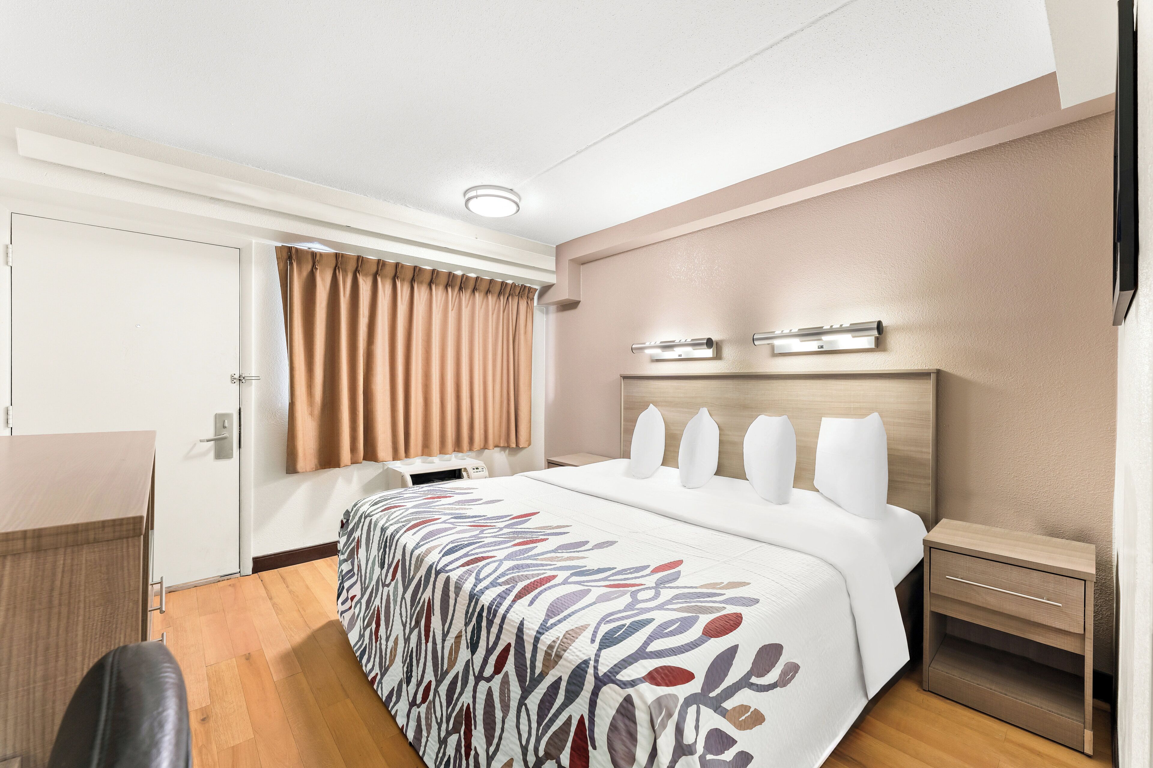 Una habitación de hotel con cama, mesitas de noche, escritorio y una silla.
