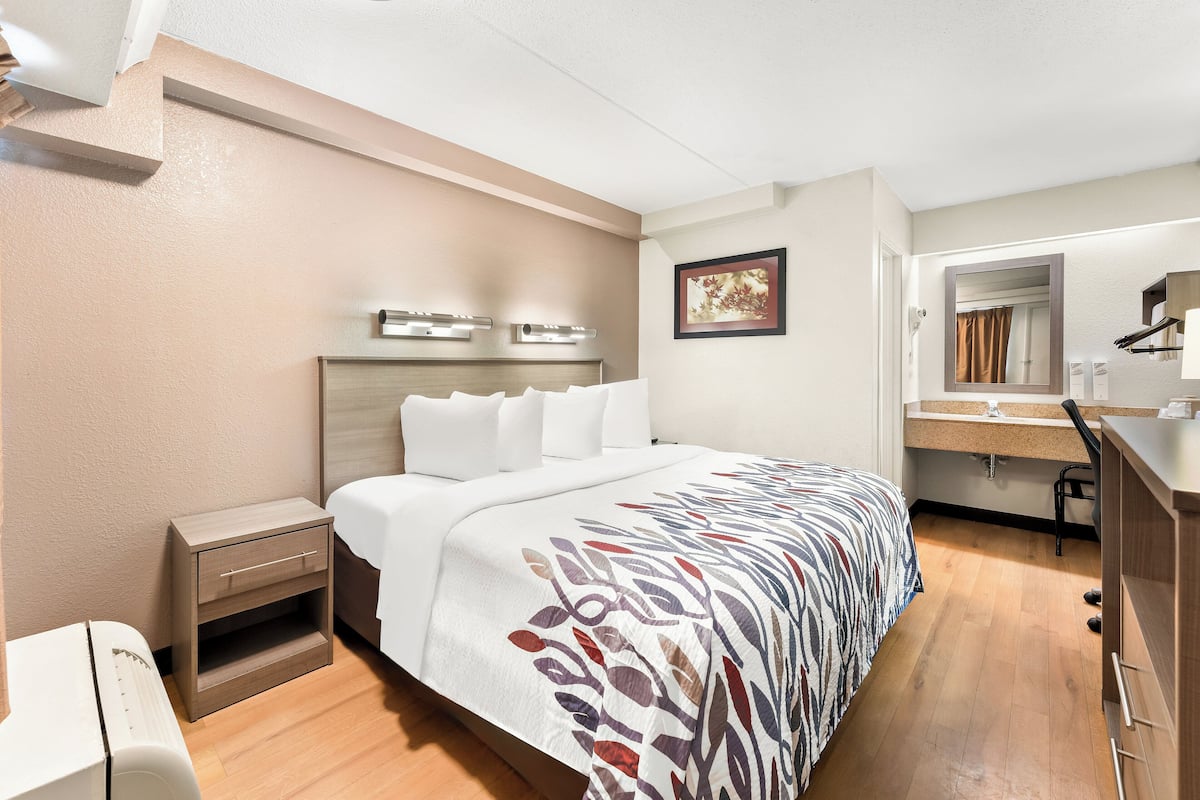 Een hotelkamer met een bed, nachtkastje en een bureau met stoel.