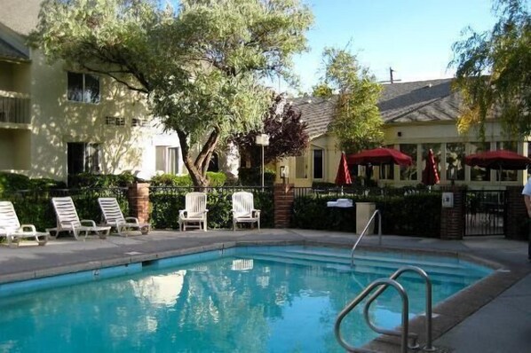 Una piscina al aire libre, sombrillas, sillones reclinables de piscina