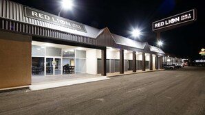 Edifício Red Lion Inn & Suites com design moderno, apresentando sinalização marcante, área de estar externa coberta e entrada bem iluminada.
