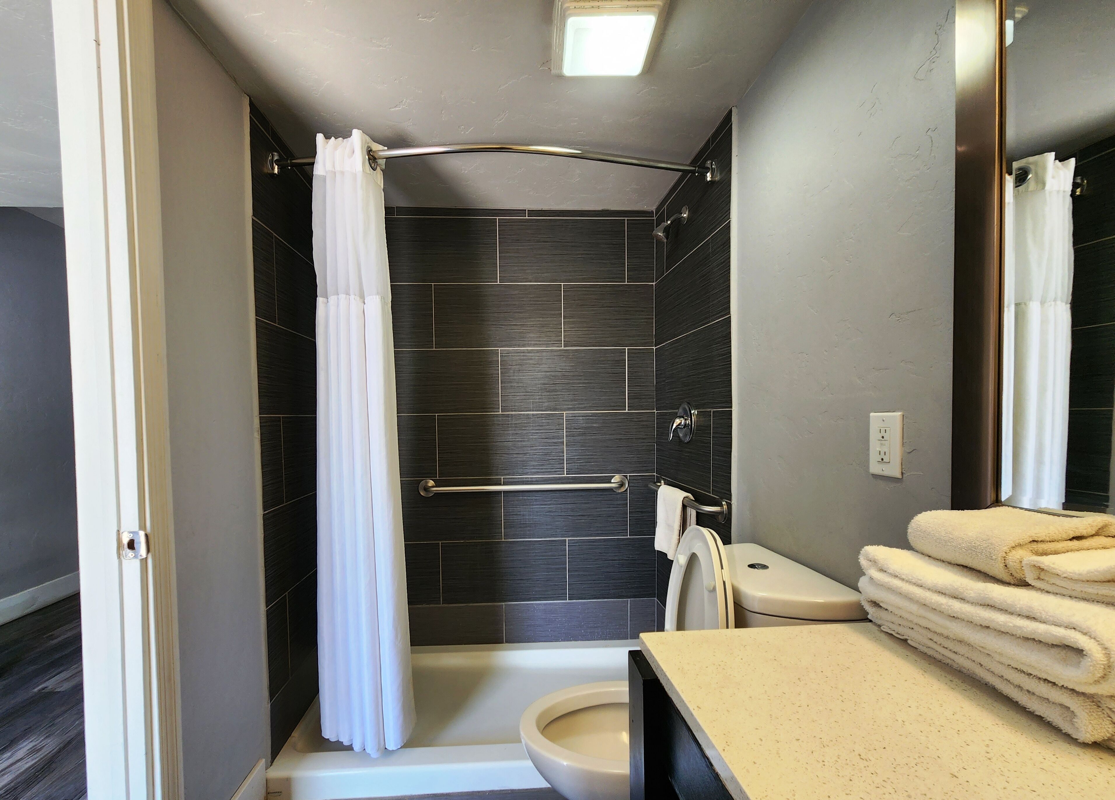 A bathroom with a shower, toilet, and a towel rack.