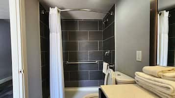 A bathroom with a shower, toilet, and a towel rack.