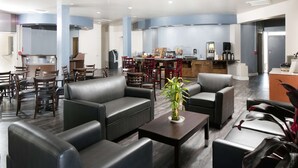 Um lobby moderno de hotel com sofás de couro, um espaço para café e uma mesa de recepção.