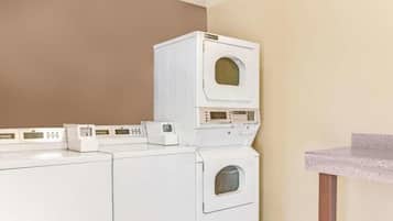 A laundry room with stacked washers and dryers, a countertop, and a wall-mounted control panel.