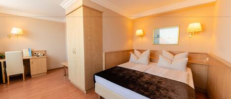 A hotel room with a bed, bedside lamps, a desk, and a wardrobe.