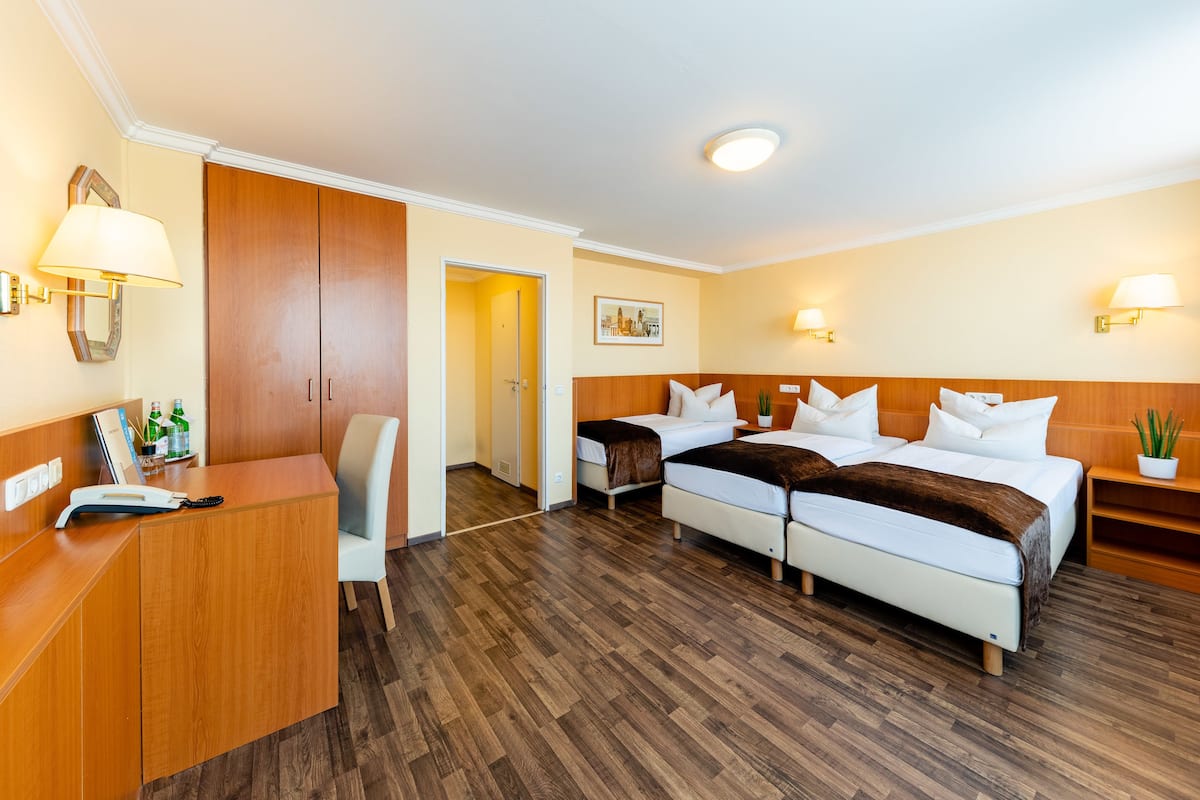 Hotellihuone, jossa on kaksi sänkyä, työpöytä, tuoli ja puinen vaatekaappi.