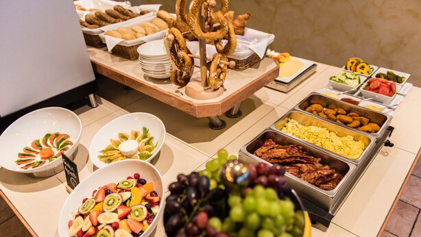 Un buffet proposant une variété de plats, notamment des fruits, des légumes et des viandes.