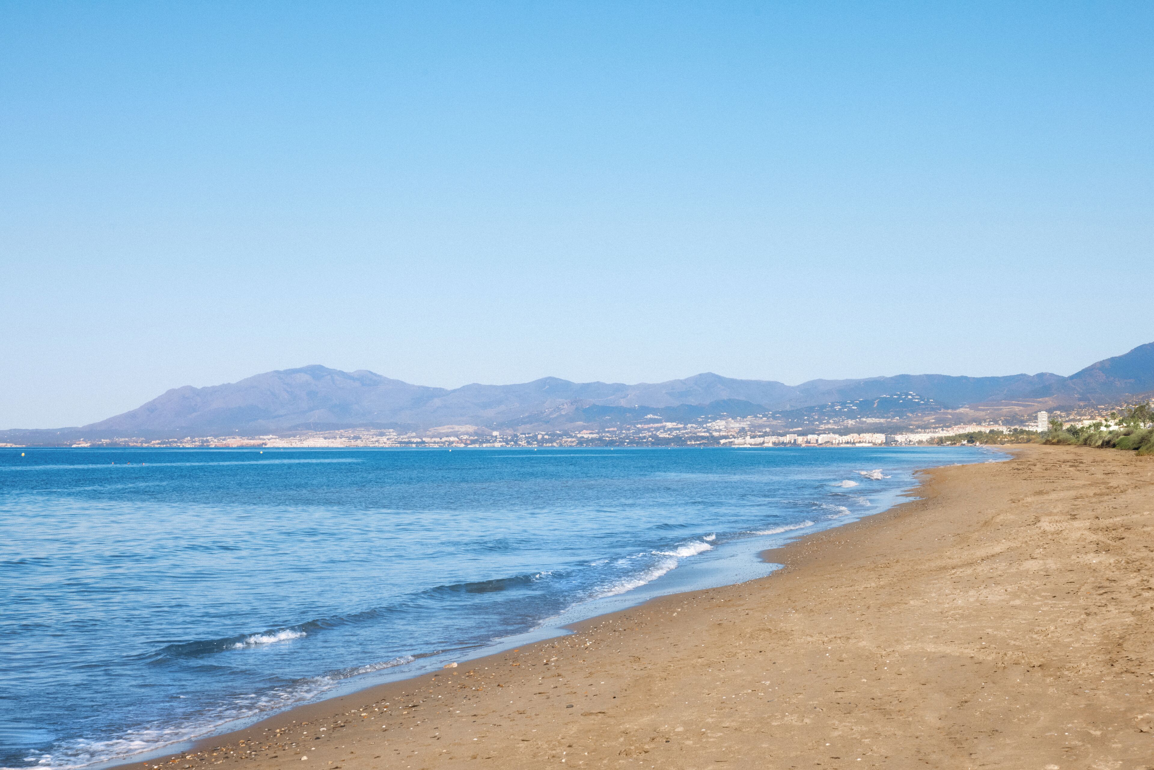 Une plage offrant une vue dégagée sur la mer et les montagnes lointaines.