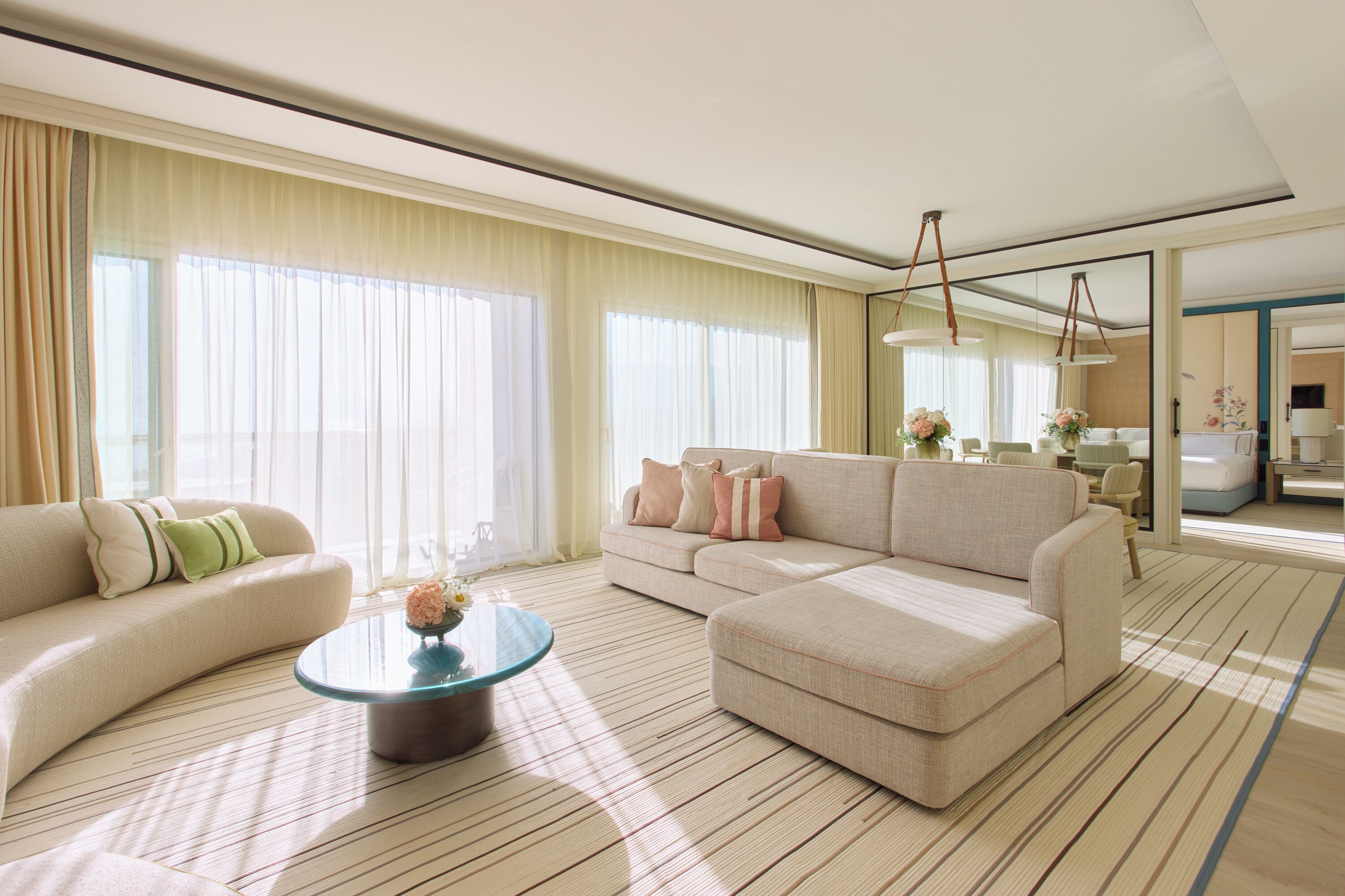 A spacious living room with a large sofa, a coffee table, and a dining area with chairs.