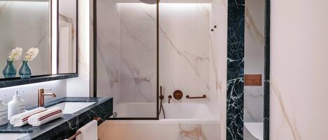 A modern bathroom with a marble sink, a glass-enclosed shower, and a large mirror.
