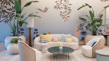 Una sala de estar moderna con un sofá, sillones, una mesa de centro y plantas grandes en macetas.