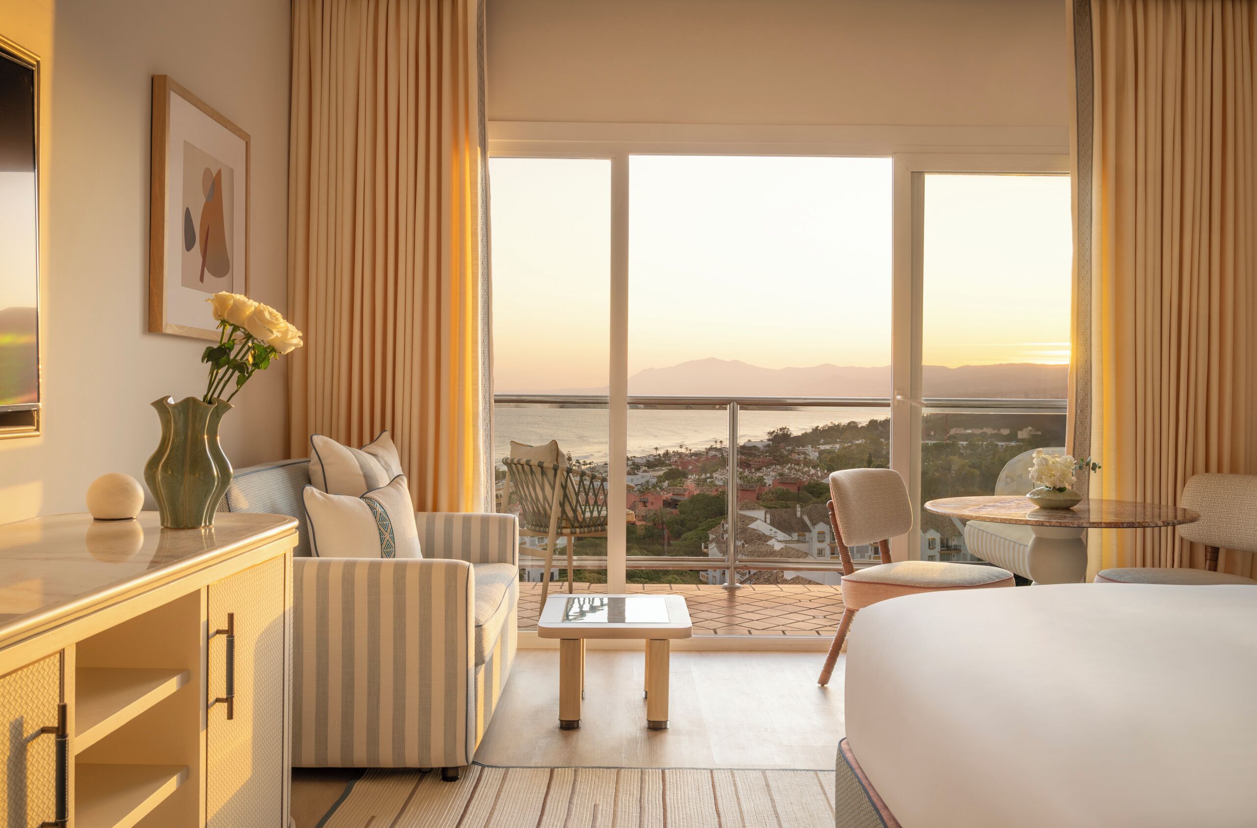 Habitación de hotel con cama, sofá, mesa de comedor y vistas a la ciudad.