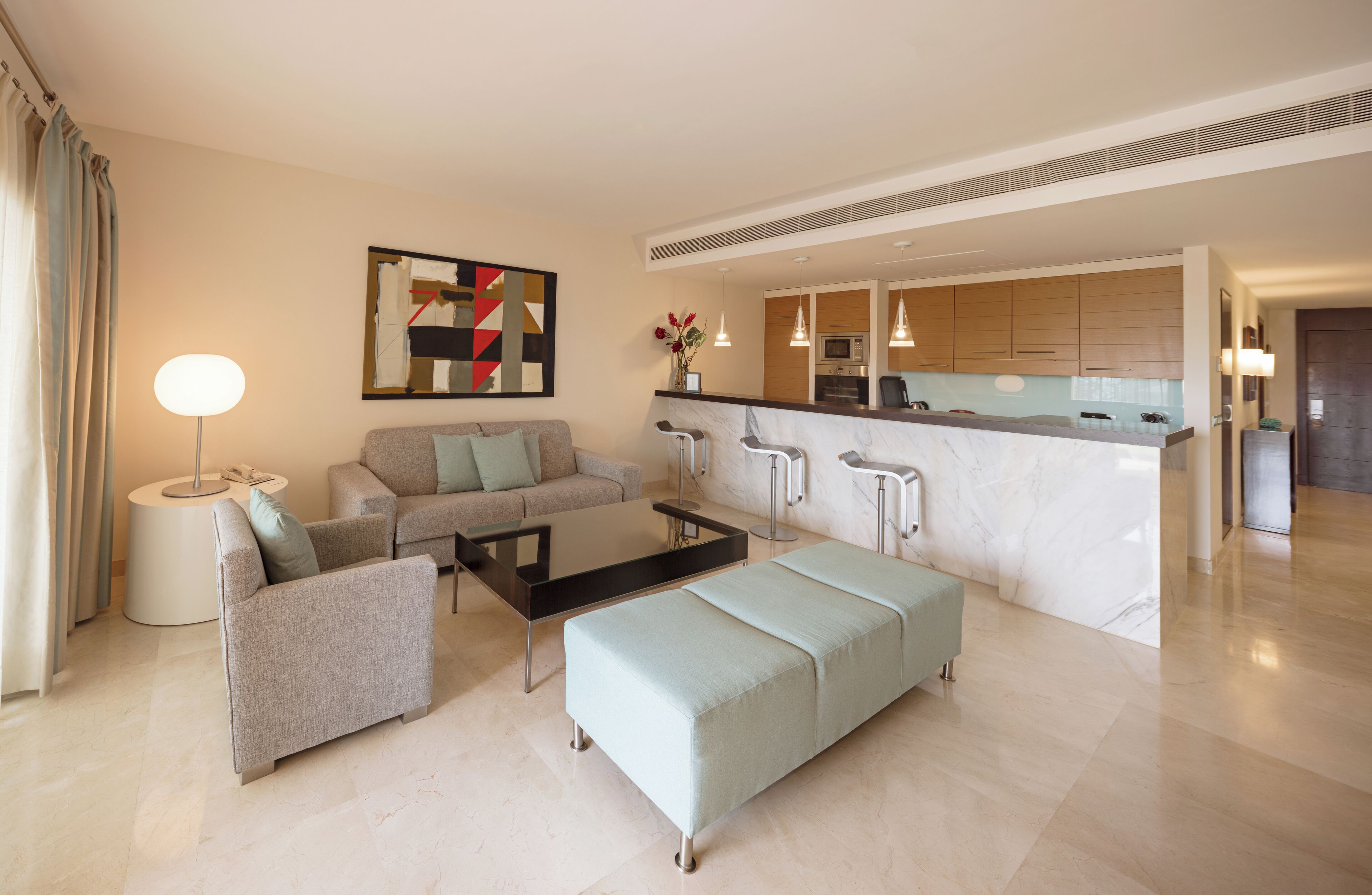 A modern living room with a sofa, a coffee table, and a dining area with a kitchen in the background.