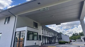A building with a sign reading "OFFICE" above the entrance, a covered walkway, and a parking lot with vehicles. - Travelodge by Wyndham Clarksville (Clarksville)